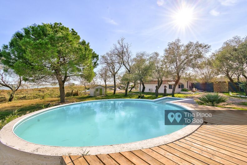 Villa with a wooden terrace and a round swimming pool