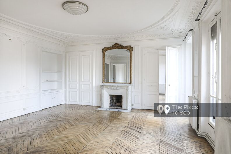 Empty Haussmannian apartment with white walls and worn parquet floors